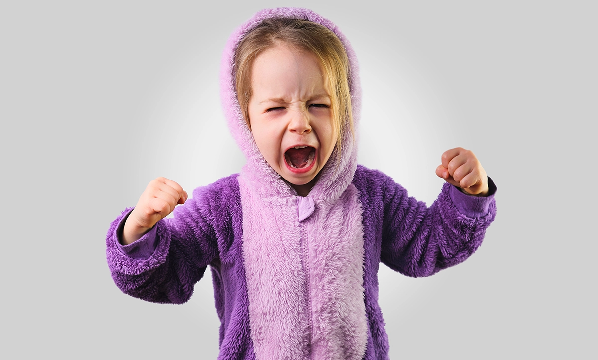 Upset toddler in purple pajamas